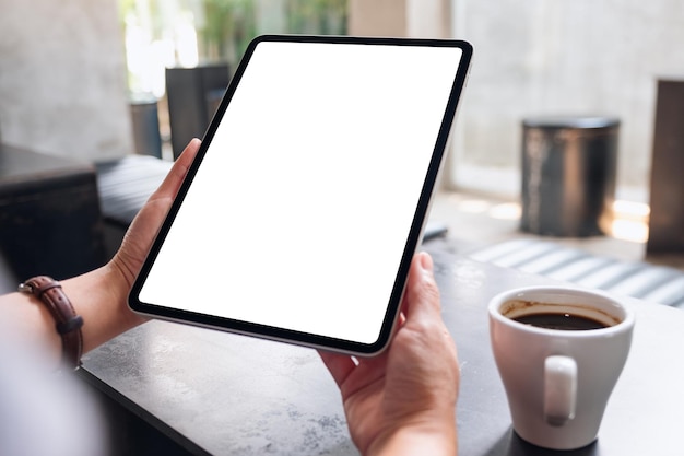 Immagine mockup di una donna in possesso di tablet digitale con schermo desktop bianco vuoto nella caffetteria