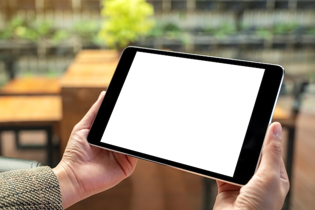 Immagine mockup di una donna seduta e in possesso di un tablet pc nero con schermo desktop bianco vuoto