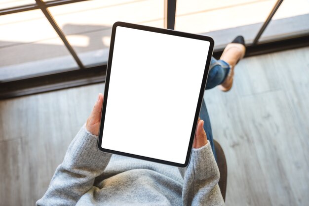 Immagine mockup vista dall'alto di una donna che tiene in mano un tablet pc nero con schermo bianco vuoto