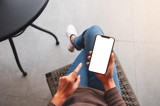 Immagine mockup vista dall'alto di una donna che tiene in mano un telefono cellulare con uno schermo desktop bianco vuoto