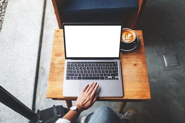 Immagine mockup vista dall'alto di una donna che usa e tocca il touchpad del laptop con uno schermo desktop bianco vuoto nella caffetteria