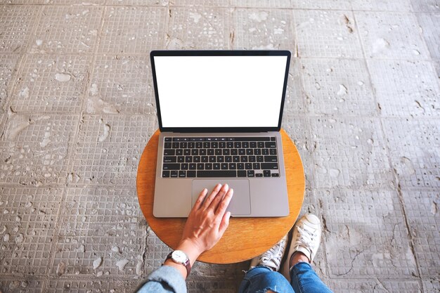 Immagine mockup vista dall'alto di una donna che usa e tocca il touchpad del laptop con uno schermo desktop bianco vuoto