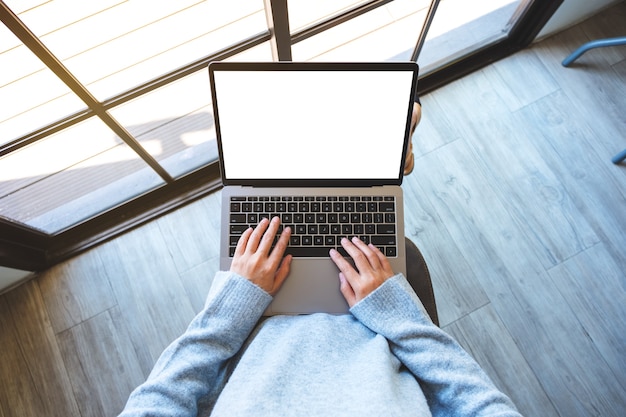 Immagine mockup vista dall'alto di una donna che utilizza e digita sul computer portatile con schermo desktop bianco vuoto