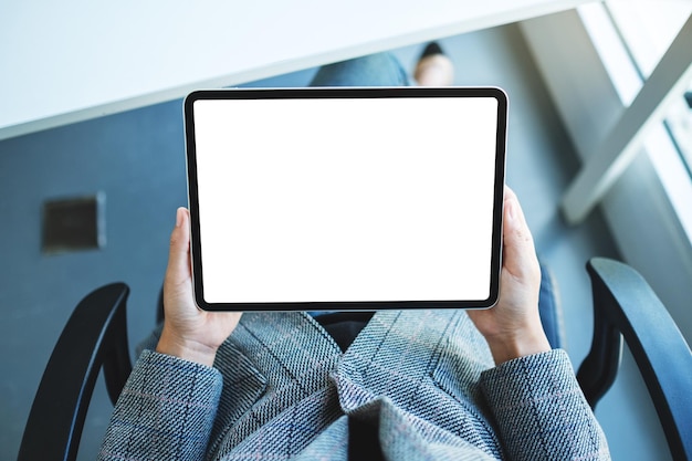 Immagine mockup vista dall'alto di una donna d'affari che tiene in mano un tablet pc nero con schermo desktop bianco vuoto