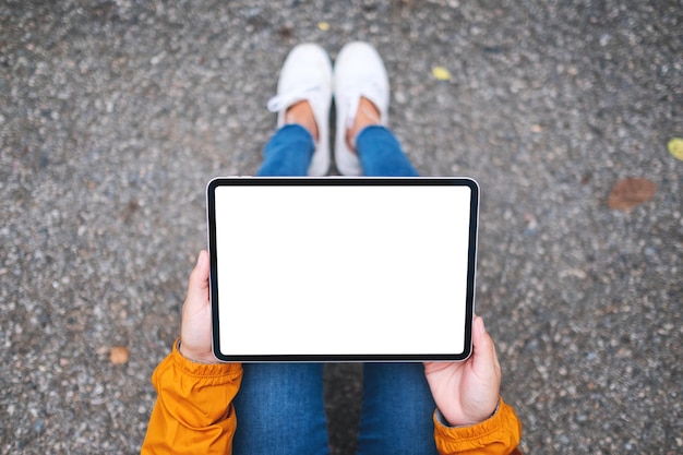 Immagine mockup vista dall'alto di una donna in possesso di tablet digitale con schermo desktop bianco vuoto in mezzo alla natura