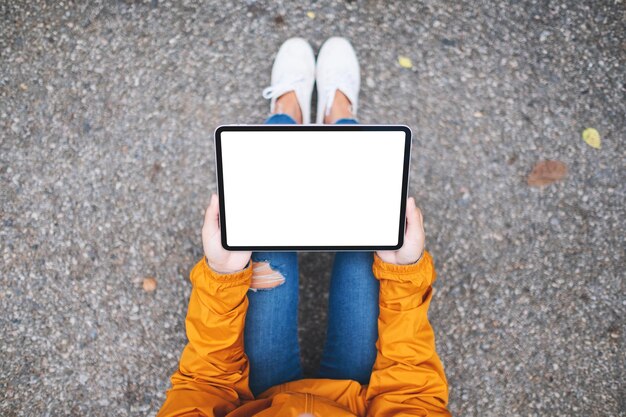 Immagine mockup vista dall'alto di una donna in possesso di tablet digitale con schermo desktop bianco vuoto in mezzo alla natura