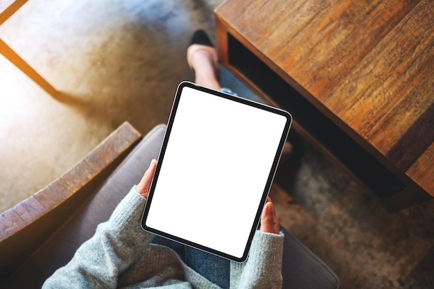 Immagine mockup vista dall'alto di una donna in possesso di tablet digitale con schermo desktop bianco vuoto