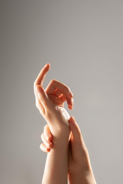 Immagine primo piano delle mani di una bella donna con manicure rosa chiaro sulle unghie Cura della pelle per le mani