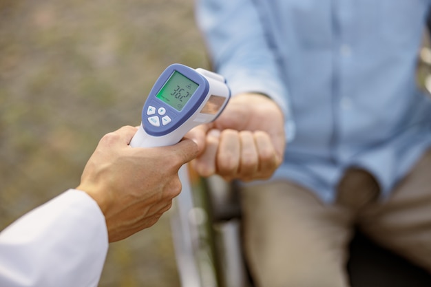 Immagine ravvicinata del termometro medico a infrarossi in una mano del medico che misura la temperatura del maschio