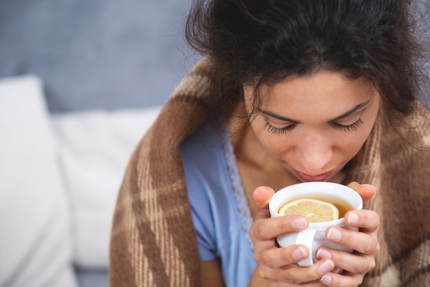 Immagine ravvicinata della giovane donna a casa con un'infezione virale