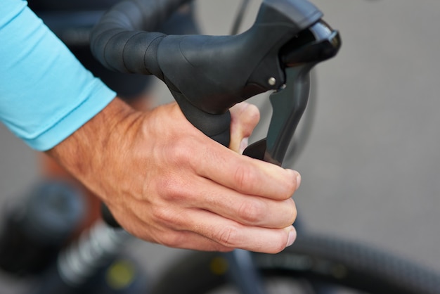 Immagine ravvicinata della mano del ciclista che spinge il freno della bicicletta sul manubrio