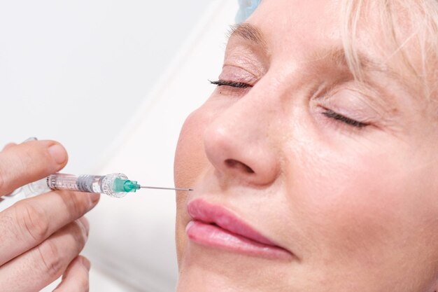 Immagine ravvicinata delle labbra che prendono iniezioni di acido ialuronico e Botox in una clinica estetica Trattamento non chirurgico per ridurre le rughe ed evitare l'invecchiamento Copia spazio per titoli e sfondo bianco