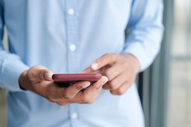 Immagine ravvicinata delle mani dell'uomo che tengono il telefono cellulare mentre si utilizza la connessione Internet wireless ad alta velocità.