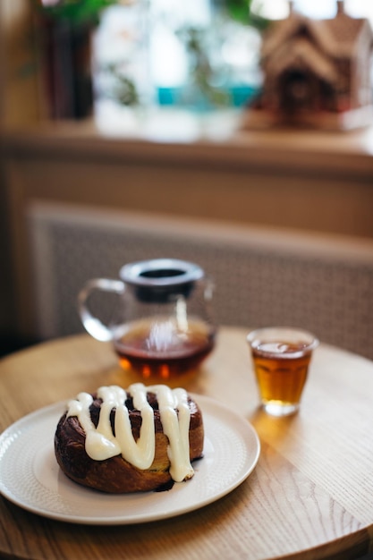 Immagine ravvicinata di delizioso Cinnabon sul tavolo con una tazza di tè e teiera