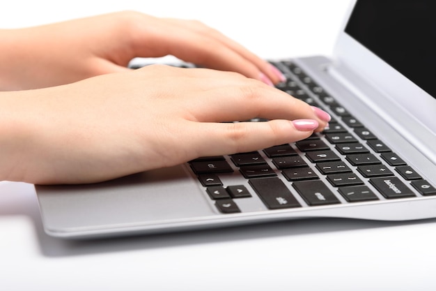 Immagine ravvicinata di mani femminili perfette che digitano su un laptop su sfondo bianco
