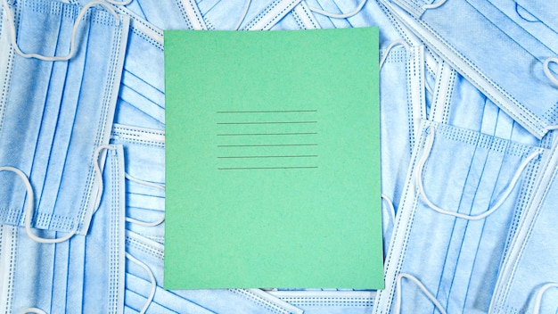 Immagine ravvicinata di maschere facciali blu e quaderno sulla scrivania