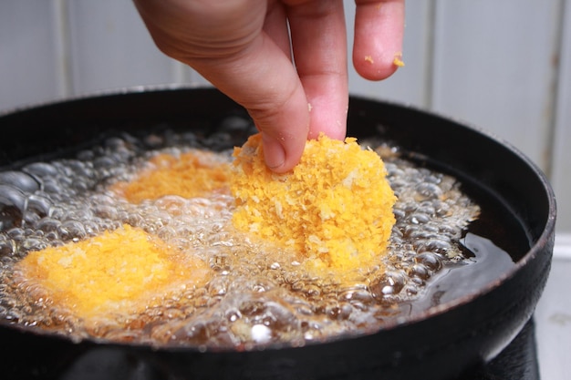 Immagine ravvicinata di un cuoco che mette le nuggets di pollo tempura in una padella ad olio caldo per la cottura a frittura