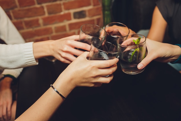 Immagine ravvicinata di un gruppo di persone tintinnio di bicchieri di vino o champagne davanti al bokeh