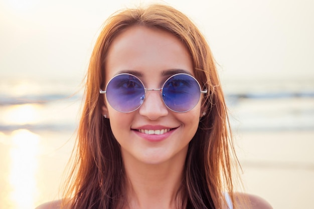 Immagine ravvicinata di una bella turista femminile che gode del tempo libero all'aperto vicino alla spiaggia dell'oceano, guarda la fotocamera durante il tempo libero in una soleggiata giornata estiva facendo selfie. Turista sorridente felice nel bacio dell'aria dei tropici