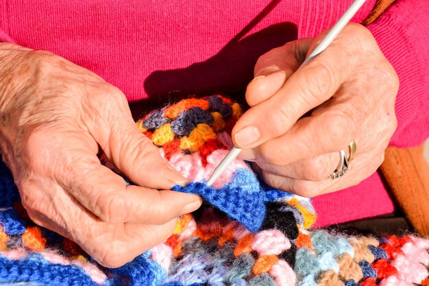 Immagine ravvicinata di una donna anziana con ferri da maglia e lana