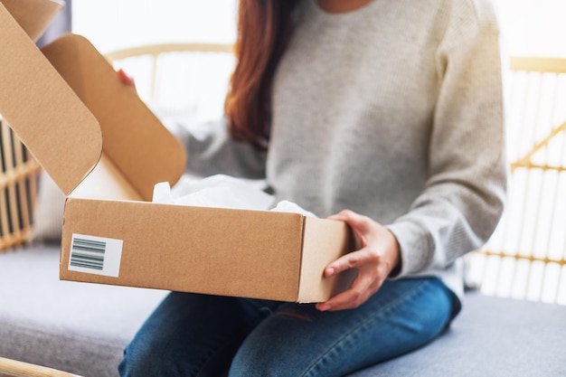 Immagine ravvicinata di una donna che riceve e apre una cassetta dei pacchi postali a casa per la consegna e il concetto di shopping online