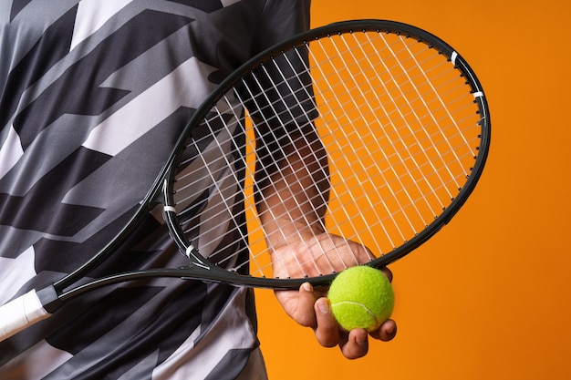 Immagine ravvicinata di una mano di giocatore di tennis con racchetta da tennis e palla