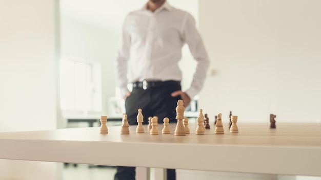 Immagine retrò di un uomo d'affari in piedi orgoglioso accanto alla sua scrivania da ufficio con figure di scacchi su di esso e re pace impostato come leader