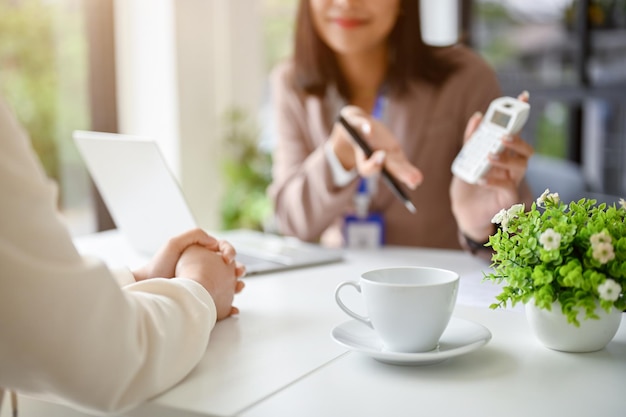 Immagine ritagliata del banchiere femminile asiatico professionista che parla con una cliente femminile in ufficio