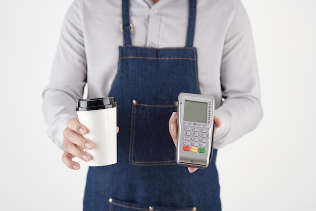 Immagine ritagliata del barista che dà una tazza di caffè da asporto e un terminale di pagamento al cliente