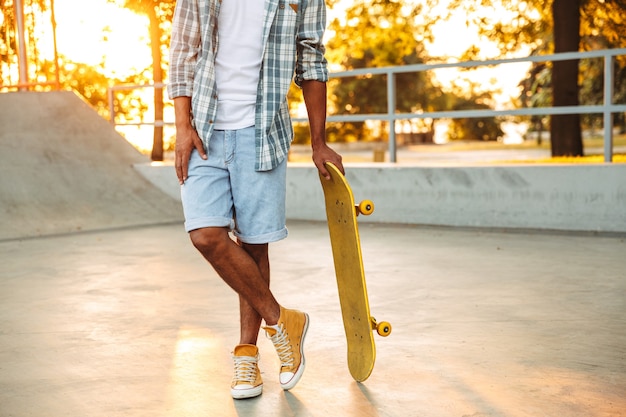 Immagine ritagliata del giovane africano con lo skateboard