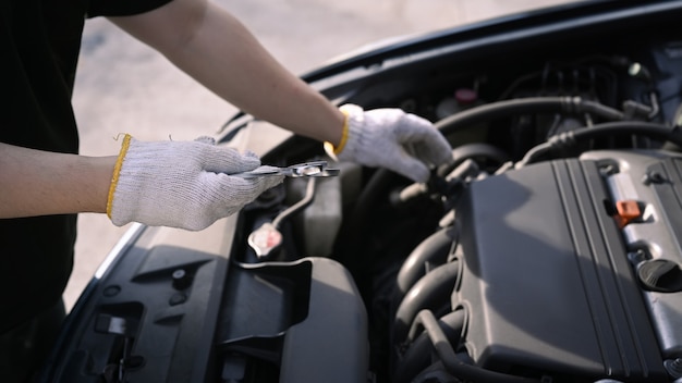 Immagine ritagliata del meccanico che ripara un motore di un'auto nel garage per auto.