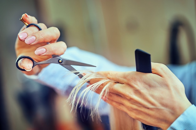 Immagine ritagliata del parrucchiere che taglia le punte dei capelli biondi