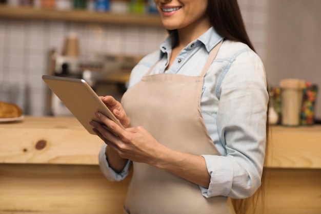 Immagine ritagliata della cameriera sorridente che utilizza la tavoletta digitale nella caffetteria