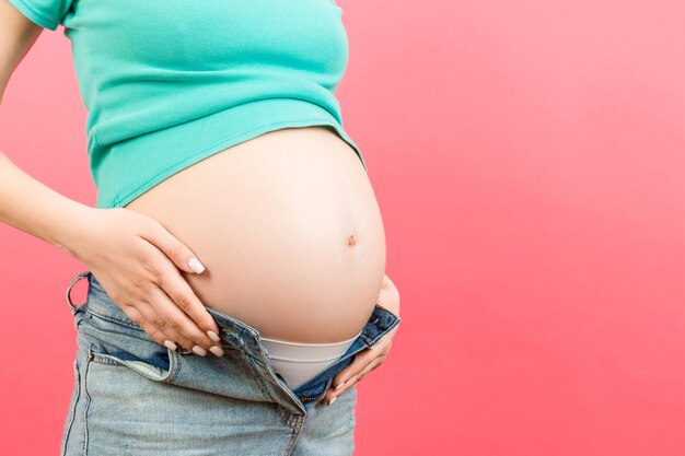 Immagine ritagliata della donna incinta in jeans decompressi che mostra il suo pancione