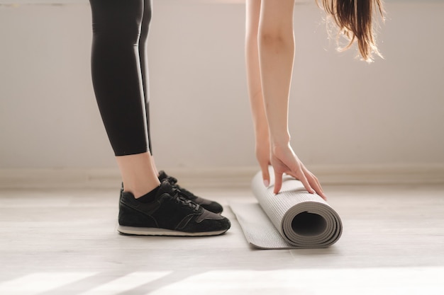 Immagine ritagliata della femmina di rotolamento materassino yoga in studio