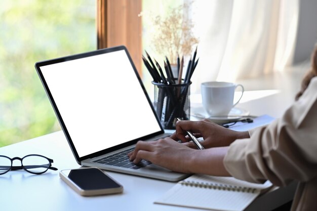 Immagine ritagliata di donna d'affari che lavora con il computer portatile in ufficio luminoso