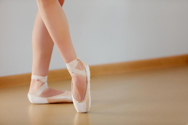 Immagine ritagliata di gambe femminili in piedi sulle punte nella scuola di balletto al chiuso Interprete di balletto classico Teneri colori pastello Concetto di coreografia di balletto classico