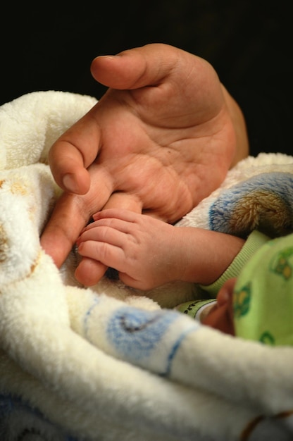 Immagine ritagliata di madre e figlio che si tengono per mano sullo sfondo nero