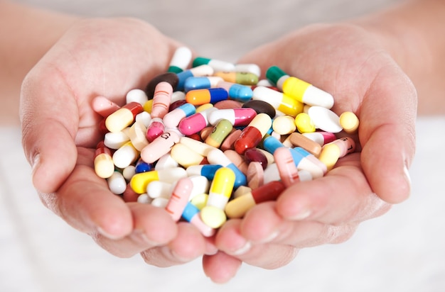 Immagine ritagliata di mani che tengono pillole e capsule su uno sfondo bianco