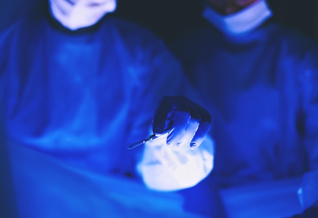 Immagine ritagliata di medici presi con bisturi che eseguono interventi chirurgici