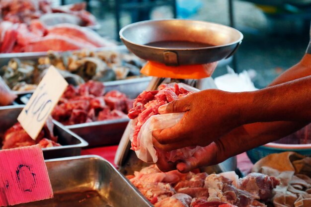 Immagine ritagliata di un macellaio che vende carne al mercato