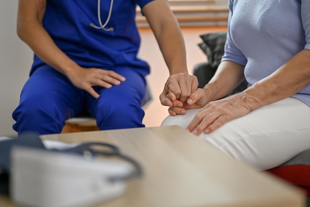 Immagine ritagliata di un medico gentile che tiene o tocca la mano di un paziente per confortarlo e sostenerlo