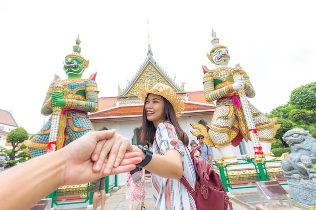 Immagine ritagliata di un uomo che tiene per mano la fidanzata in piedi contro il tempio