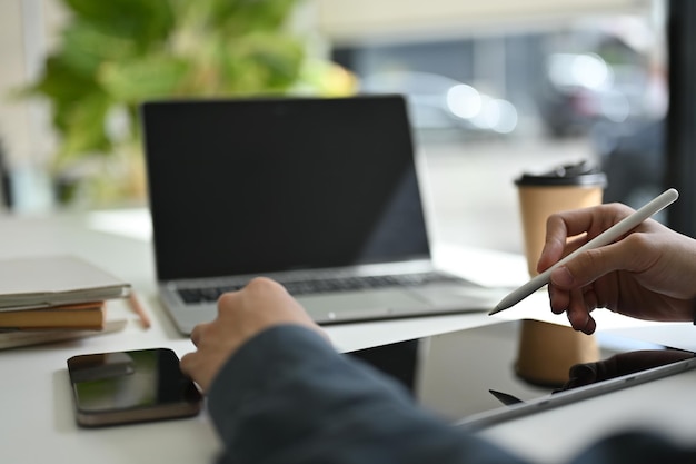 Immagine ritagliata di un uomo d'affari o di un impiegato di sesso maschile che utilizza il suo tablet digitale alla scrivania dell'ufficio