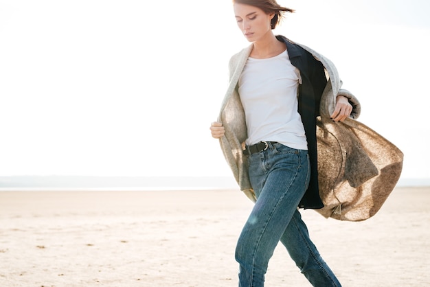 Immagine ritagliata di una bella donna casual che cammina in riva al mare alla luce del sole