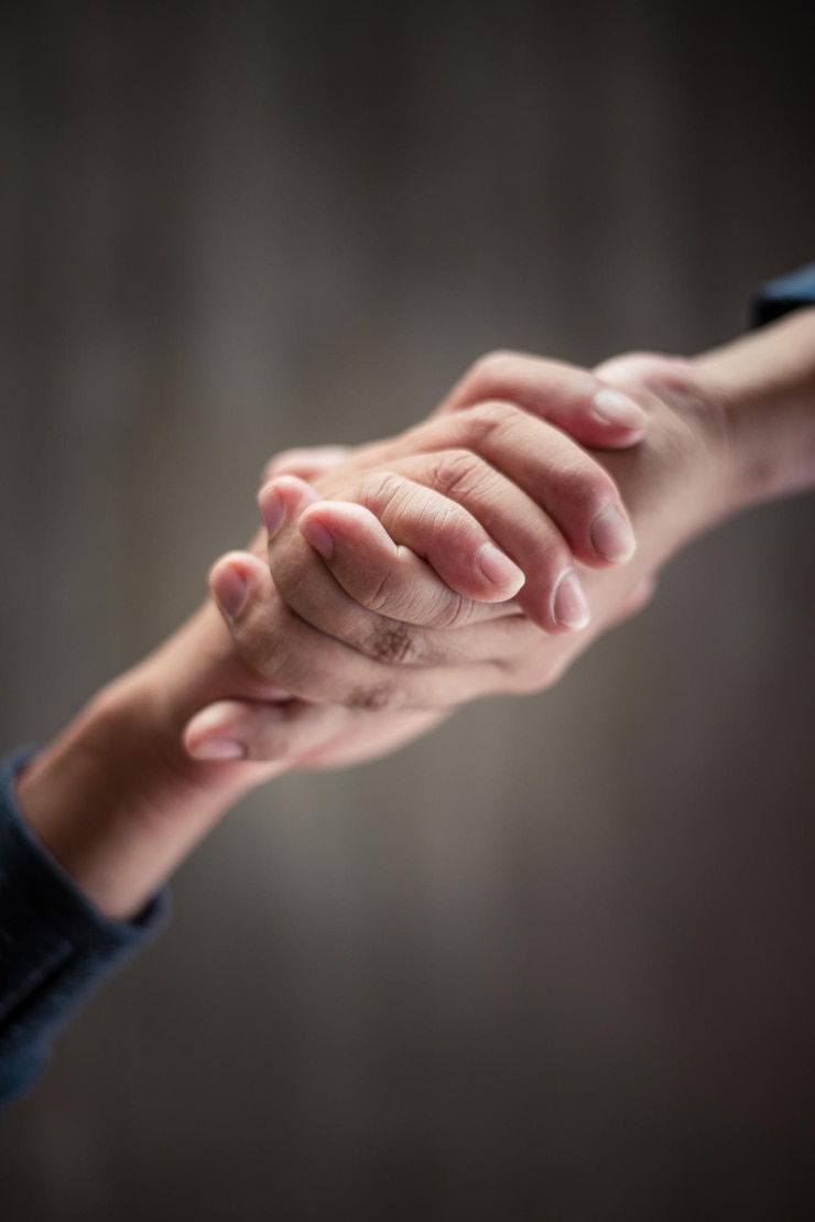 Foto immagine ritagliata di una coppia che si tiene per mano contro il muro