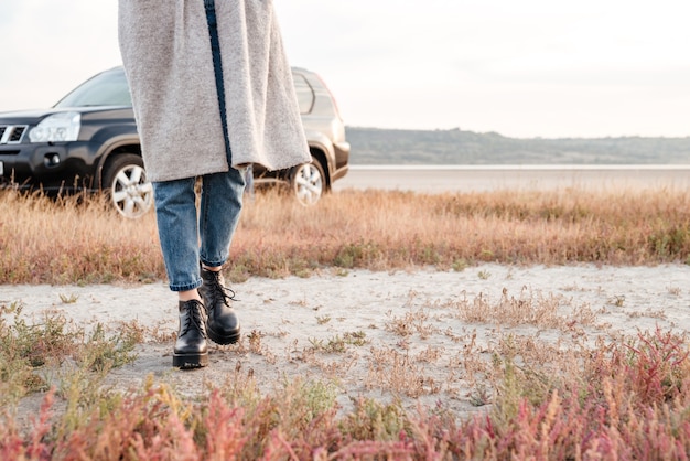 Immagine ritagliata di una donna casual che cammina fuori con l'auto sullo sfondo