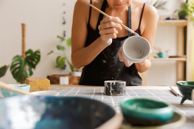 Immagine ritagliata di una donna che fa stoviglie in ceramica e ceramica al laboratorio