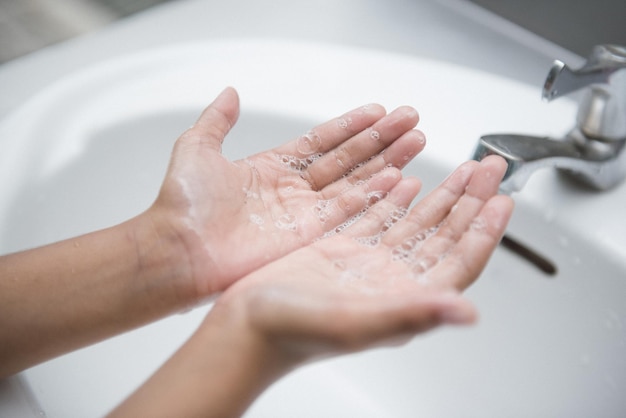 Immagine ritagliata di una donna che si lava le mani nel lavandino a casa