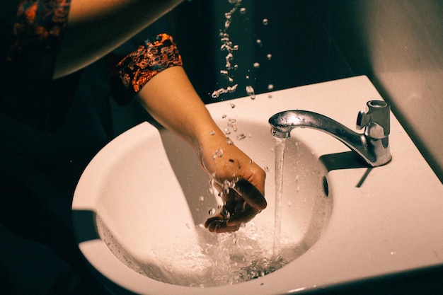 Immagine ritagliata di una donna che si lava le mani nel lavandino